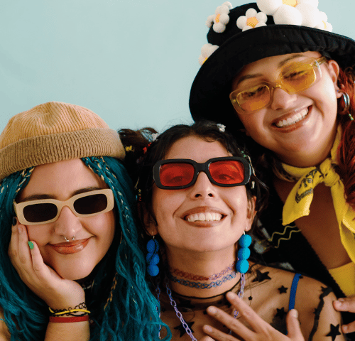 Image of three young women posing for a photo, smiling together.