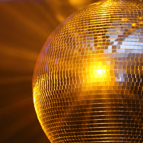 Disco Ball with yellow light shining on it.